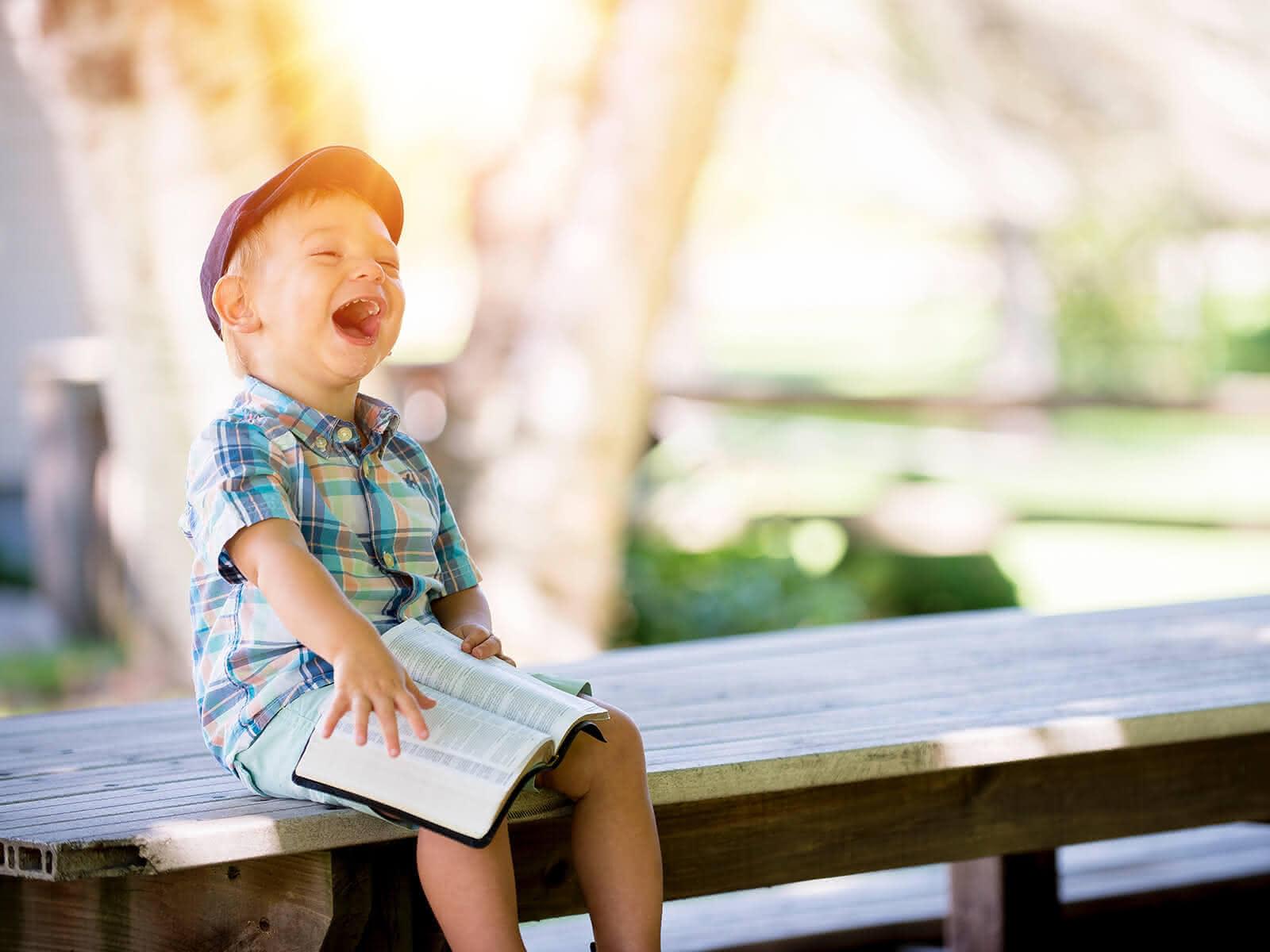 Lachendes Kind mit Buch (c) CC0 1.0 - Public Domain (von unsplash.com) Lachendes Kind mit Buch